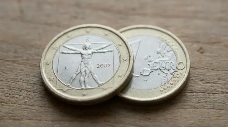 Due monete da 1 euro su un tavolo, con dettaglio dell’anno 2002 in primo piano