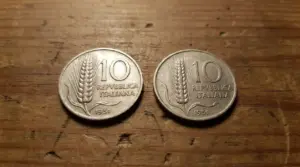 Due monete da 10 lire del 1951 affiancate su un tavolo di legno, con spiga di grano e scritta Repubblica Italiana