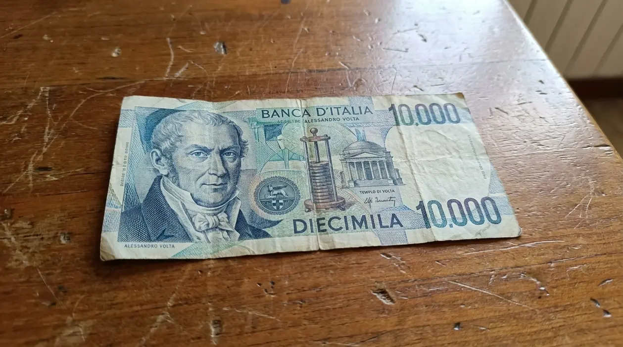 Banconota italiana da 10.000 lire con Alessandro Volta appoggiata su un tavolo di legno