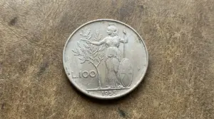 Moneta da 100 lire Minerva 1955 su superficie in pelle, con figura femminile e ramo d’ulivo
