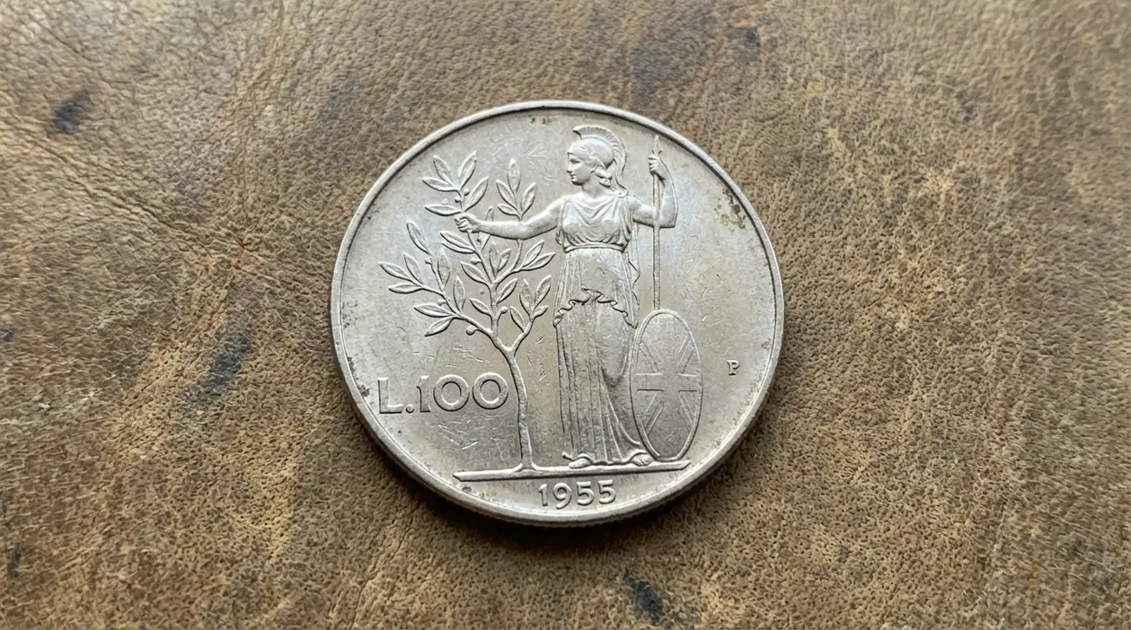 Moneta da 100 lire Minerva 1955 su superficie in pelle, con figura femminile e ramo d’ulivo