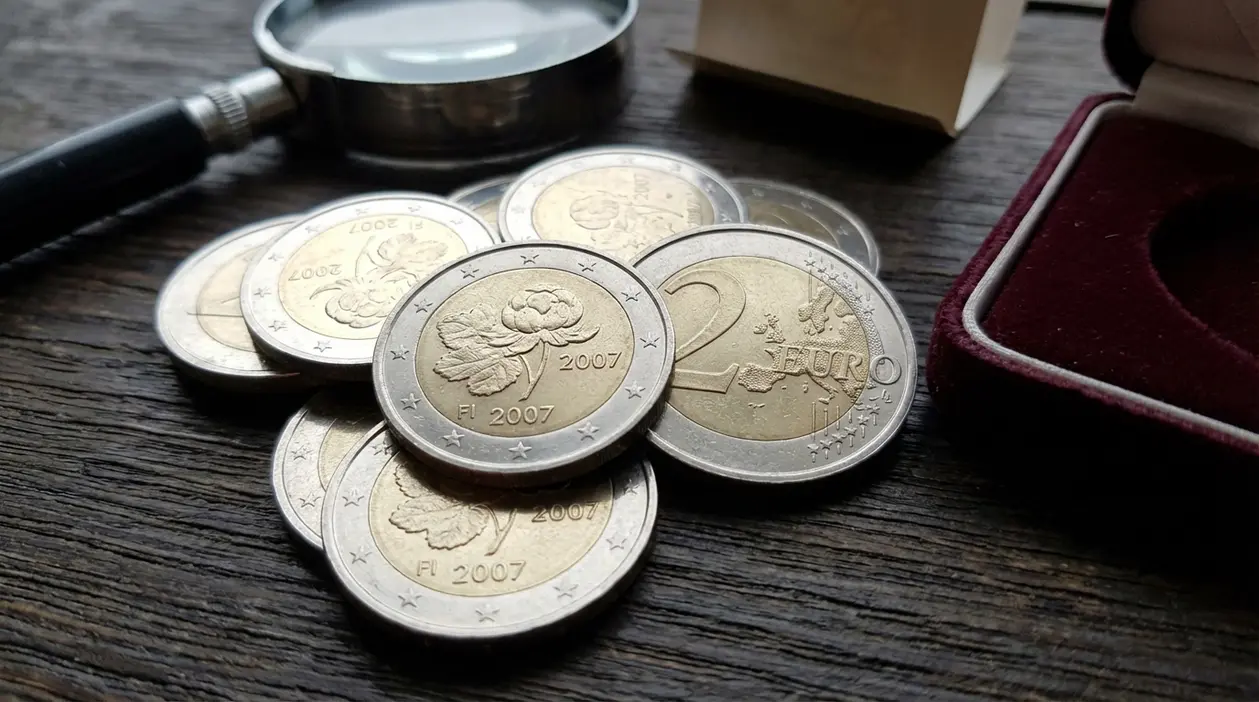 Monete da 2 euro Finlandia 2007 commemorative su tavolo, con lente d’ingrandimento e custodia da collezione