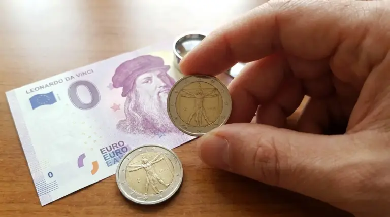 Mano che mostra una moneta da 2 euro con Leonardo da Vinci accanto a una banconota commemorativa