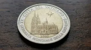 Moneta da 2 euro del Vaticano 2005 con facciata della cattedrale e iscrizione commemorativa, su superficie in legno