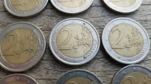 Monete da 2 euro su tavolo in legno, dettaglio delle stelle sul bordo in evidenza