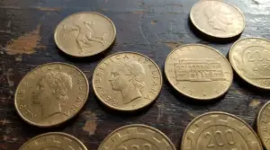 Monete da 200 lire italiane commemorative e ordinarie disposte su un tavolo di legno
