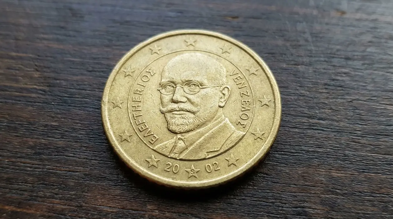 Moneta da 50 centesimi euro della Grecia 2002 con ritratto, appoggiata su superficie in legno