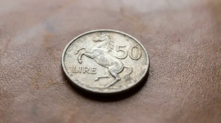 Moneta italiana da 50 lire con cavallino rampante appoggiata su una superficie marrone