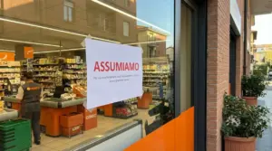 Cartello di assunzione sulla vetrina di un supermercato, simbolo dei settori in espansione e della ricerca di personale