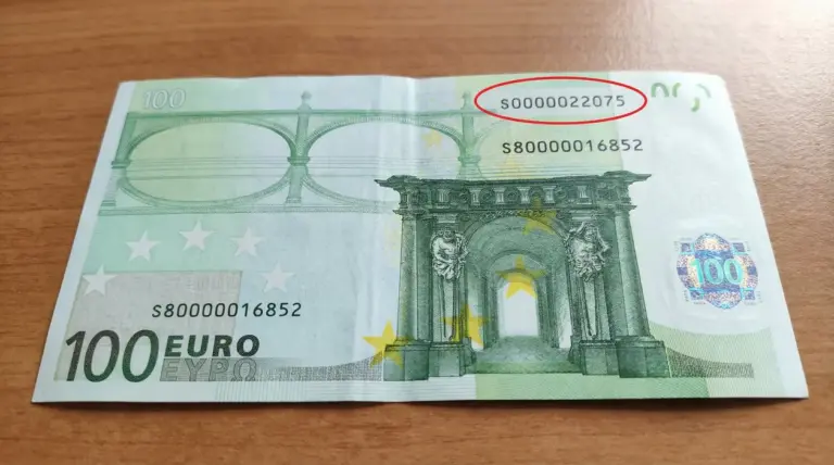 Banconota da 100 euro appoggiata su un tavolo, con numero di serie evidenziato
