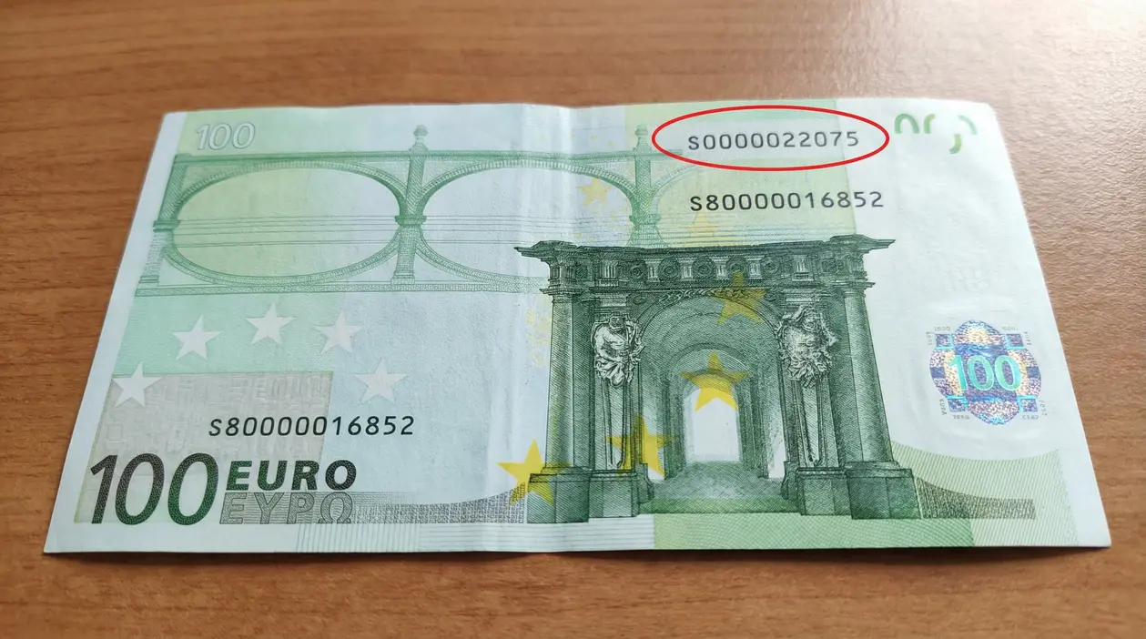 Banconota da 100 euro appoggiata su un tavolo, con numero di serie evidenziato