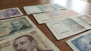 Banconote italiane d'epoca con numeri seriali particolari disposte su un tavolo in legno