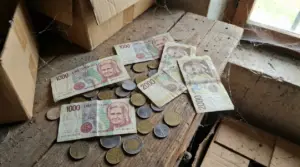 Vecchie banconote e monete in lire italiane su un tavolo polveroso accanto a scatole di cartone