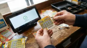 Una persona controlla un gratta e vinci con un terminale su un bancone di tabaccheria