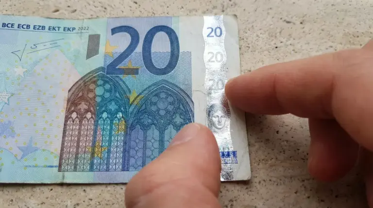 Dettaglio di una banconota da 20 euro controllata da una mano per verificarne l'autenticità