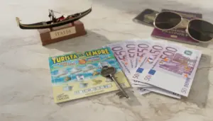 Gratta e vinci Turista per sempre con banconote da 50 euro, una chiave e accessori da viaggio su un tavolo