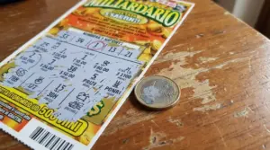 Biglietto Gratta e Vinci su un tavolo di legno accanto a una moneta da un euro