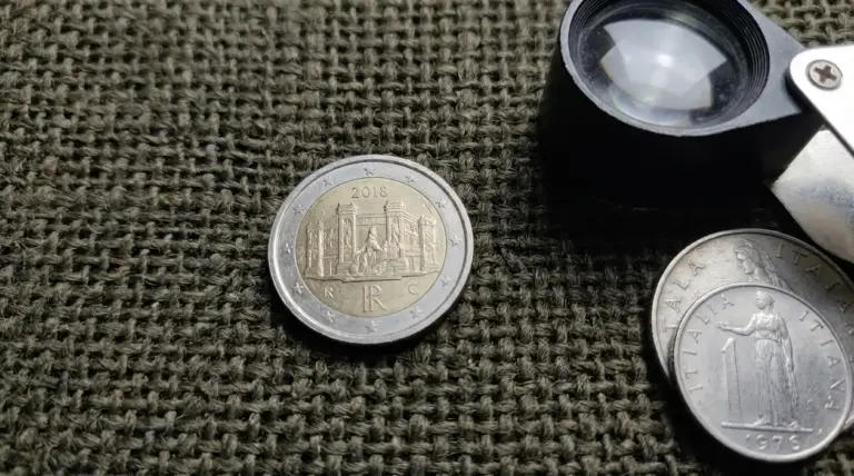 Moneta da 2 euro su tessuto con lente d’ingrandimento e altre monete, tema microerrore e valore di mercato