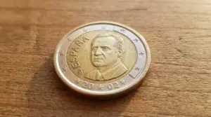 Moneta da 1 euro spagnola con ritratto maschile appoggiata su una superficie di legno