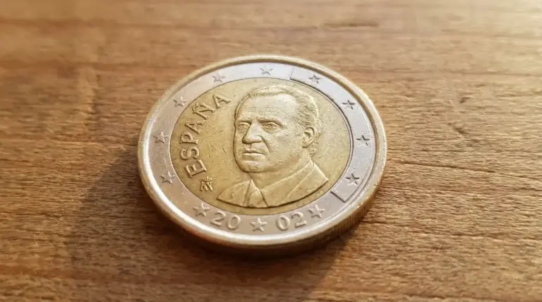 Moneta da 1 euro spagnola con ritratto maschile appoggiata su una superficie di legno