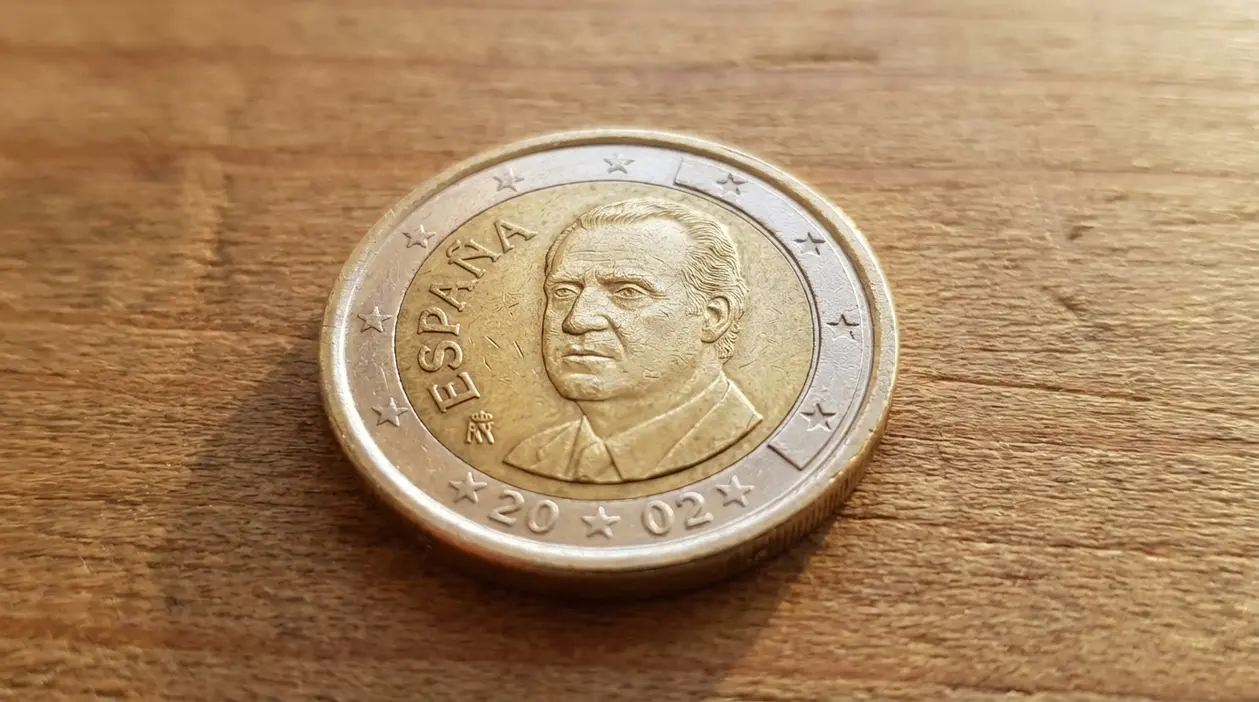 Moneta da 1 euro spagnola con ritratto maschile appoggiata su una superficie di legno