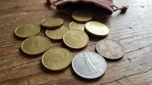 Monete da 20 centesimi sparse su un tavolo di legno accanto a un piccolo sacchetto, tema monete rare di valore