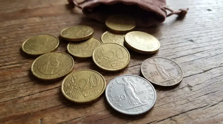 Monete da 20 centesimi sparse su un tavolo di legno accanto a un piccolo sacchetto, tema monete rare di valore