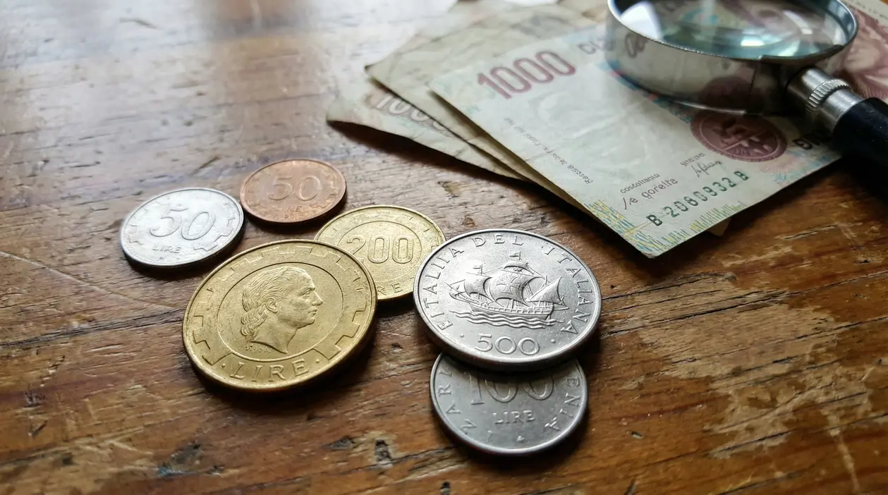 Monete e banconote italiane in lire su un tavolo di legno
