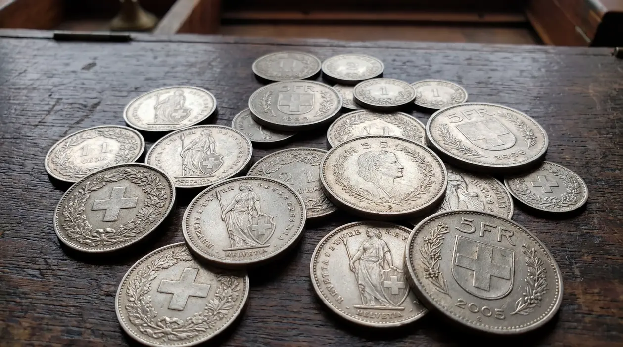 Monete svizzere in argento di diversi tagli sparse su un tavolo in legno