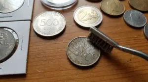 Spazzolina su monete rare e da collezione appoggiate su un tavolo di legno