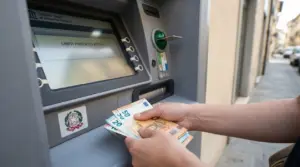 Persona ritira banconote in euro da uno sportello bancomat, tema limiti ai prelievi automatici