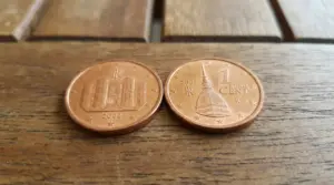 Due monete da 1 centesimo del 2002 appoggiate su un tavolo di legno, fotografate da vicino