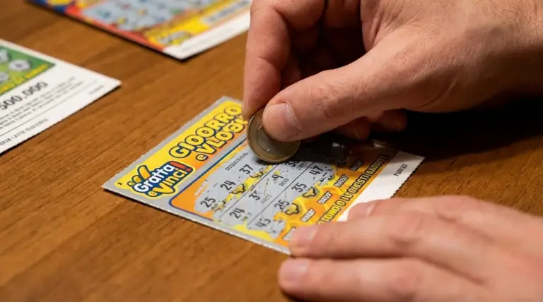 Persona che gratta un biglietto Gratta e Vinci con una moneta su un tavolo di legno