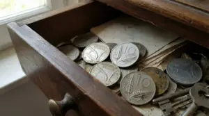 Vecchie monete da 10 lire con la spiga in un cassetto di legno insieme ad altri oggetti.