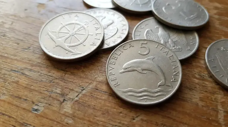 Monete da 5 lire con il delfino della Repubblica Italiana appoggiate su un tavolo di legno