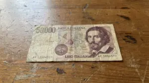 Vecchia banconota italiana da 50000 lire appoggiata su un tavolo di legno