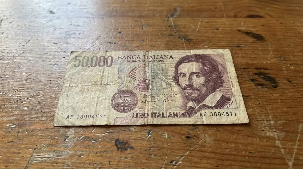 Vecchia banconota italiana da 50000 lire appoggiata su un tavolo di legno