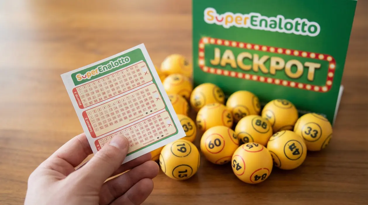 Mano che tiene una schedina del SuperEnalotto accanto a palline numerate e cartello verde del jackpot