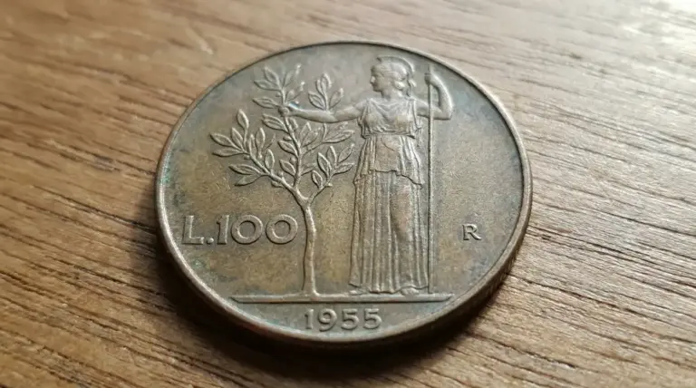 Moneta da 100 lire del 1955 appoggiata su un tavolo di legno, vista in primo piano