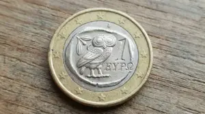 Moneta da 1 euro con gufo incisa sul lato nazionale, appoggiata su una superficie di legno