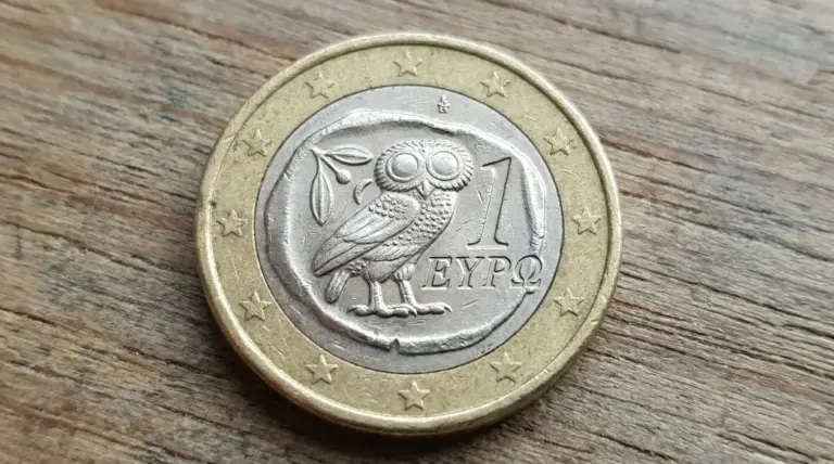 Moneta da 1 euro con gufo incisa sul lato nazionale, appoggiata su una superficie di legno